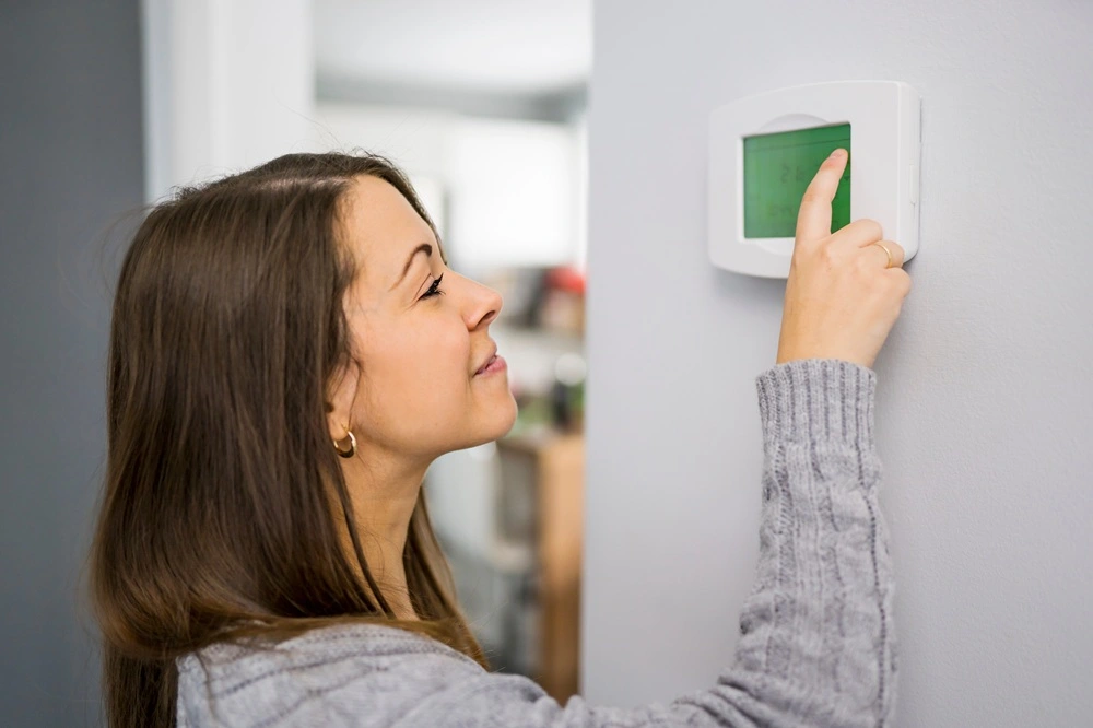 Homeowner checking thermostat because furnace won't turn on