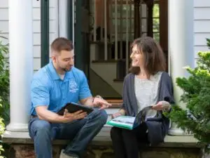 A man and woman relax on their porch, discussing home energy assessments with Homeworks Energy, a Mass Save partne