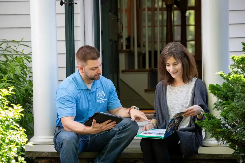 A man and woman relax on their porch, discussing home energy assessments with Homeworks Energy, a Mass Save partne