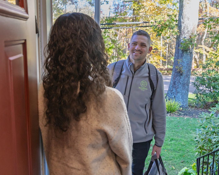Home Energy Specialist greets a Massachusetts homeowner at her front door for a no-cost Mass Save Home Energy Assessment