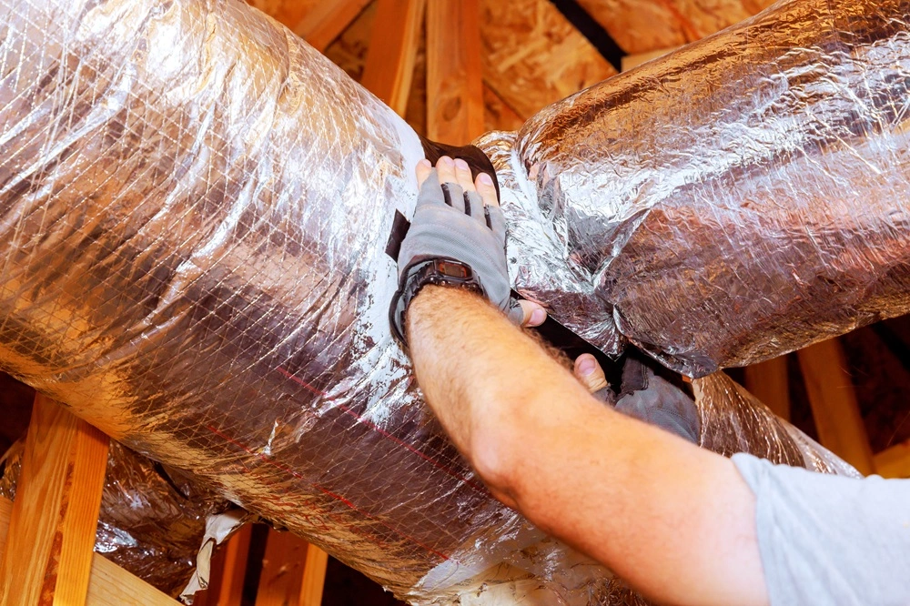 HVAC contractor fixing insulation around leaky ductwork