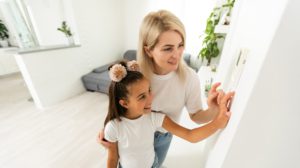 Mother and Daughter with Programmable Smart Thermostat in Home