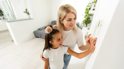 Mother and Daughter with Programmable Smart Thermostat in Home