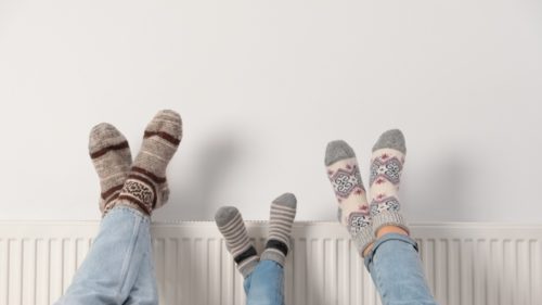 Family props their feet up on the radiator with cozy winter socks