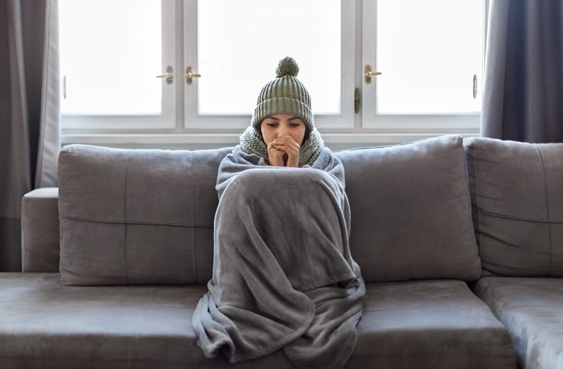 Woman Bundled up on the Couch in a Cold Room in Her New England Home