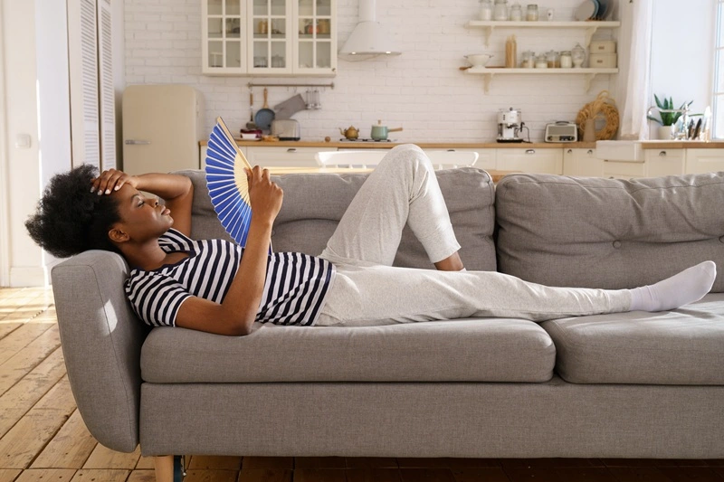 Massachusetts Woman Fanning Herself on Couch in Her Home