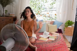 Young Woman with Fan Hot Summer High Energy Bills HVAC Causes