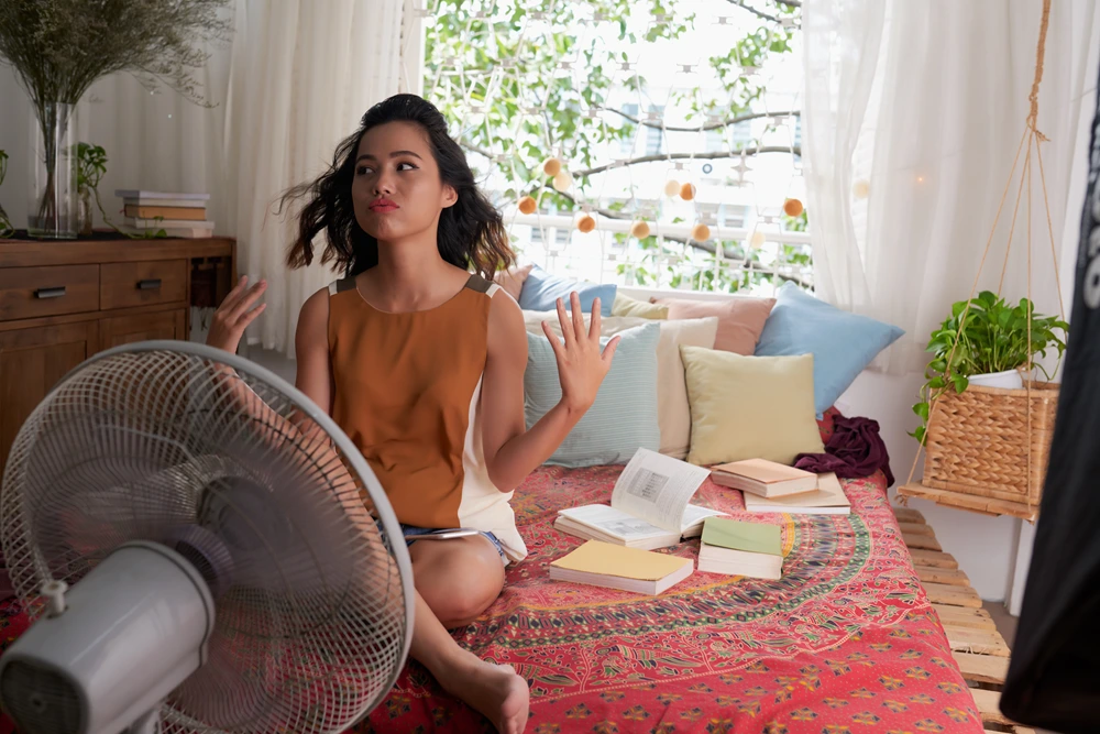 Young Woman with Fan Hot Summer High Energy Bills HVAC Causes