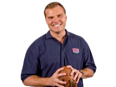 Scott Zolak A cutout of Scott Zolak from the waist up holding a football and smiling at the camera.